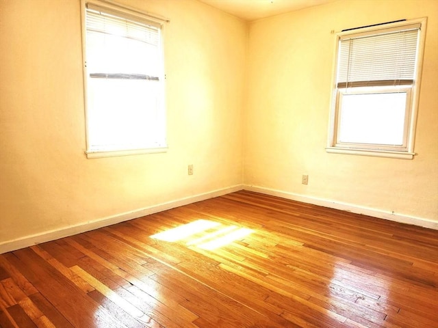 spare room featuring baseboards and hardwood / wood-style flooring