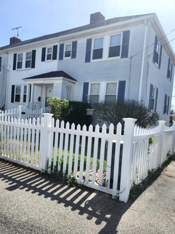 colonial-style house featuring a fenced front yard and a chimney