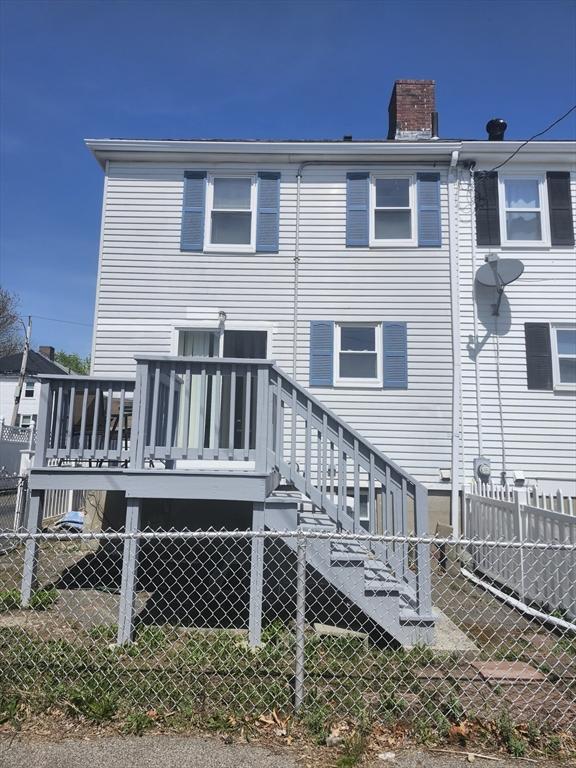 rear view of property featuring a deck, a chimney, and a fenced backyard