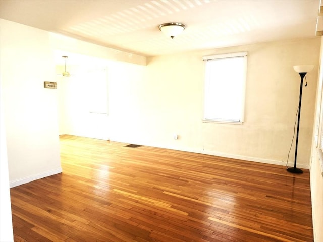 empty room featuring visible vents, baseboards, and hardwood / wood-style flooring