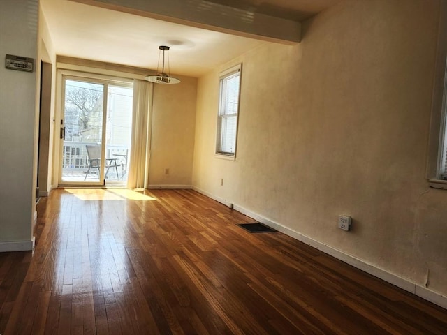 spare room with baseboards, plenty of natural light, dark wood-style flooring, and visible vents