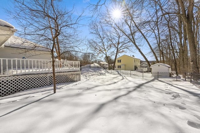 yard layered in snow featuring fence and a wooden deck