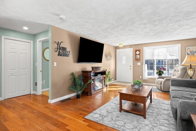 living room with a textured ceiling, baseboards, and wood finished floors