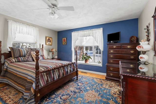 bedroom with visible vents, ceiling fan, baseboards, and wood finished floors