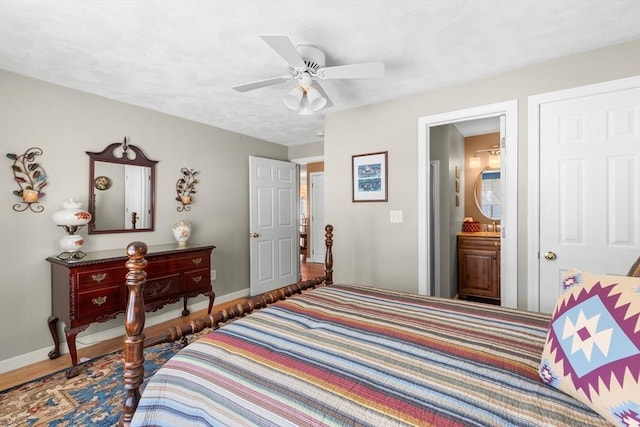 bedroom featuring a ceiling fan, ensuite bath, and baseboards