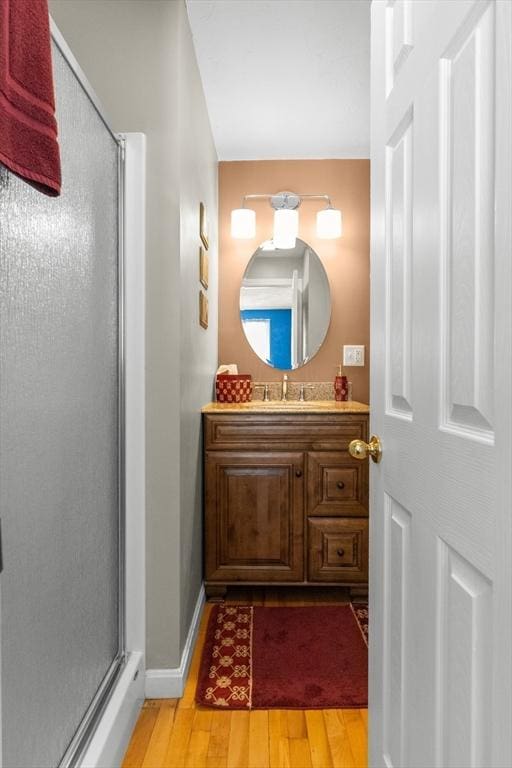 bathroom featuring a stall shower, wood finished floors, vanity, and baseboards