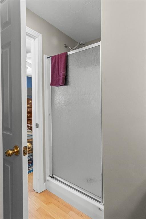 full bath featuring a shower stall and wood finished floors