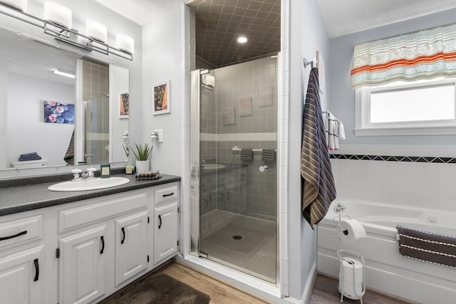 full bath with a shower stall, wood finished floors, a bath, and vanity