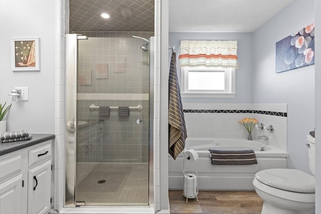 bathroom with toilet, wood finished floors, vanity, a shower stall, and a bath