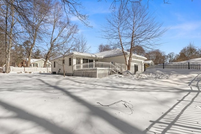 view of snow covered exterior featuring a deck, fence, and a chimney