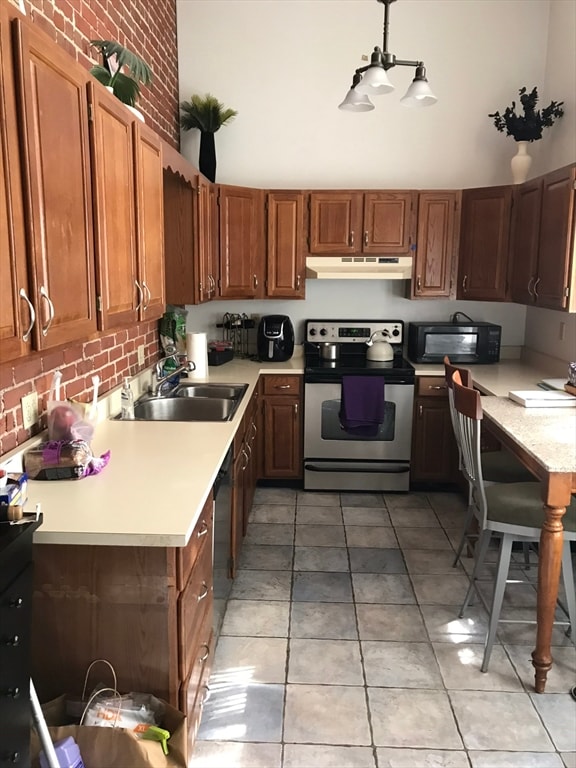 kitchen featuring pendant lighting, stainless steel electric range, sink, light tile patterned floors, and brick wall