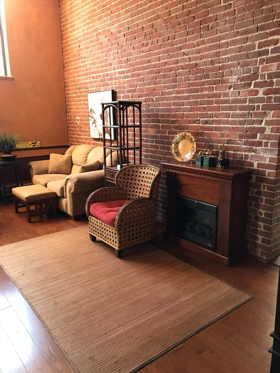 sitting room with hardwood / wood-style floors and brick wall