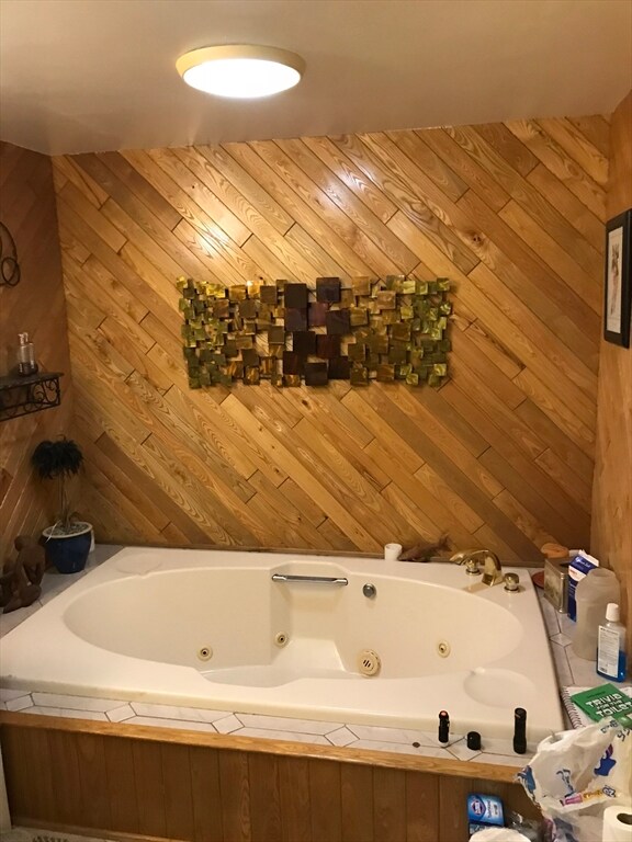 bathroom featuring wood walls and a bathtub