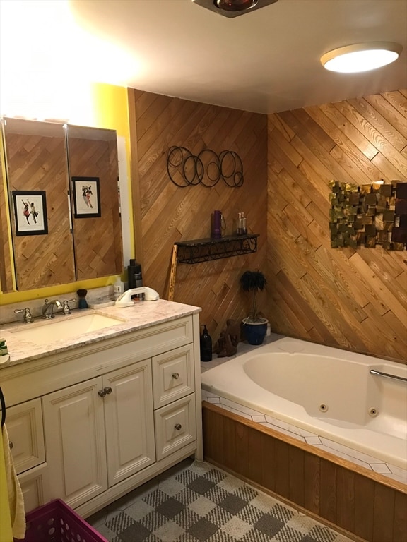 bathroom featuring vanity, a relaxing tiled tub, and wooden walls