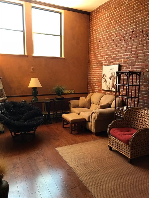 interior space with wood-type flooring, crown molding, and brick wall