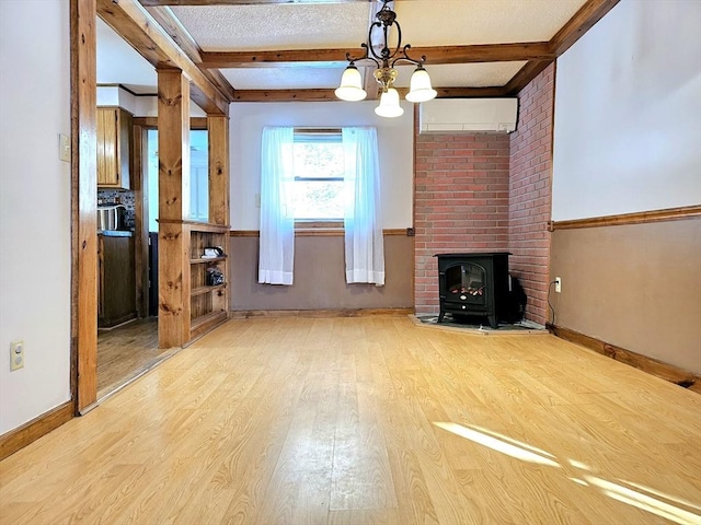 unfurnished living room with beam ceiling, light hardwood / wood-style floors, a wall mounted AC, and a wood stove