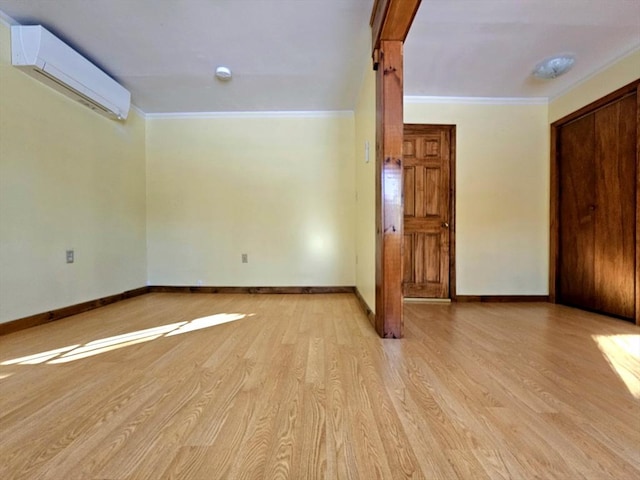 empty room featuring ornamental molding, a wall mounted air conditioner, and light wood-type flooring