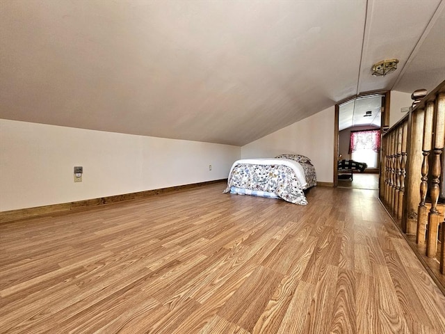 unfurnished bedroom featuring lofted ceiling and light hardwood / wood-style floors