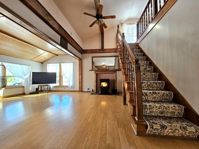 unfurnished living room featuring lofted ceiling, hardwood / wood-style floors, a fireplace, and ceiling fan