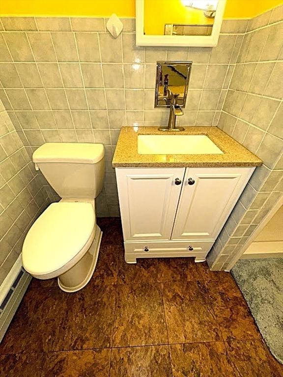 330 Chapin St, Ludlow, MA 01056 - half bath with tile walls, vanity, toilet, and a baseboard radiator