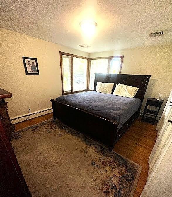 330 Chapin St, Ludlow, MA 01056 - bedroom featuring baseboard heating, wood finished floors, a textured ceiling, and baseboards