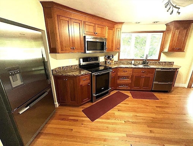 330 Chapin St, Ludlow, MA 01056 - kitchen featuring stainless steel appliances, light wood finished floors, a sink, brown cabinets, and dark stone counters