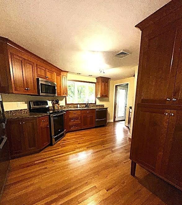 330 Chapin St, Ludlow, MA 01056 - kitchen with appliances with stainless steel finishes, a sink, a textured ceiling, dark wood-style flooring, and dark countertops