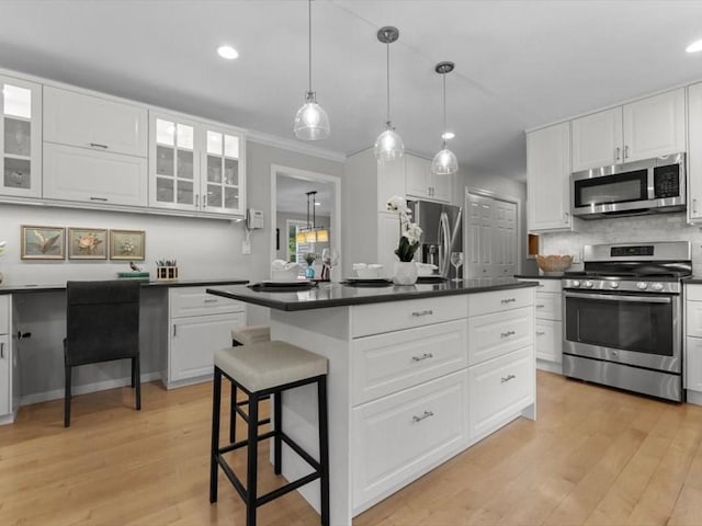29 Shermans Way, Westwood, MA 02090 - kitchen featuring appliances with stainless steel finishes, dark countertops, a center island, white cabinets, and ornamental molding