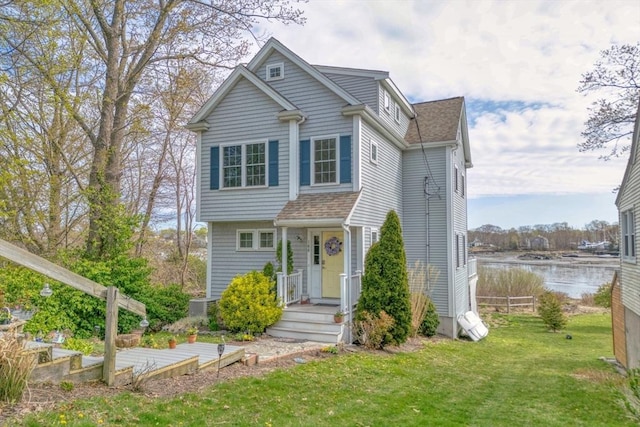 view of front of home with a water view, a front lawn, fence, and a shingled roof