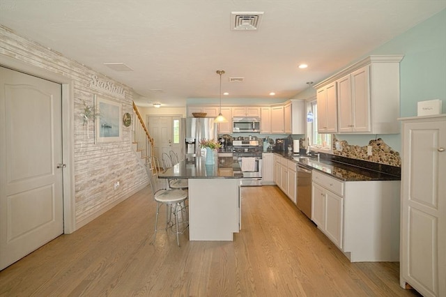 kitchen featuring a kitchen breakfast bar, a kitchen island, stainless steel appliances, and white cabinetry
