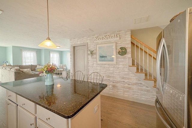 kitchen featuring light wood-style flooring, dark stone countertops, freestanding refrigerator, white cabinetry, and open floor plan