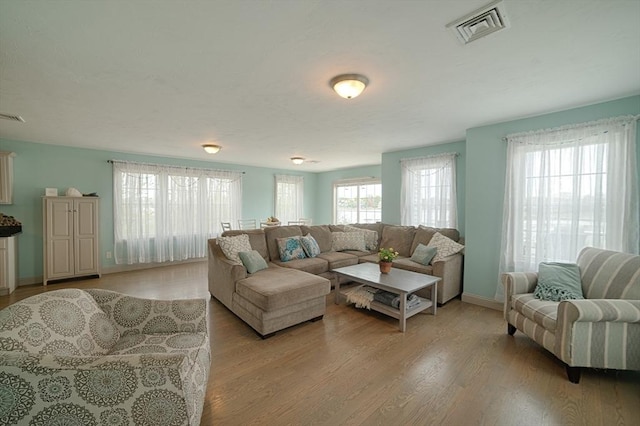 living room featuring baseboards, visible vents, and light wood-style flooring