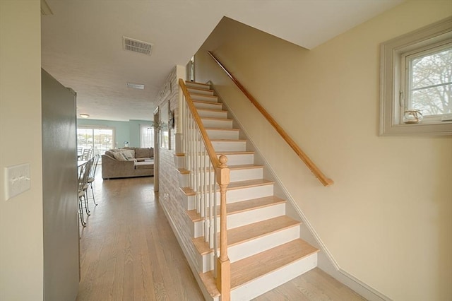 stairway featuring visible vents and wood finished floors