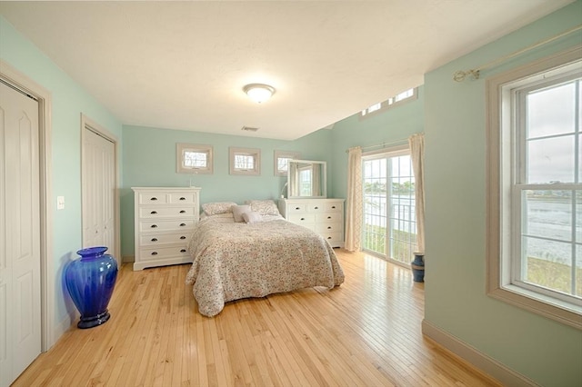 bedroom featuring baseboards, light wood finished floors, two closets, and visible vents