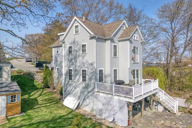 back of house with a storage unit, stairs, a wooden deck, an outdoor structure, and a yard