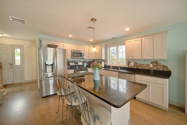 kitchen with a sink, appliances with stainless steel finishes, light wood-style flooring, and visible vents