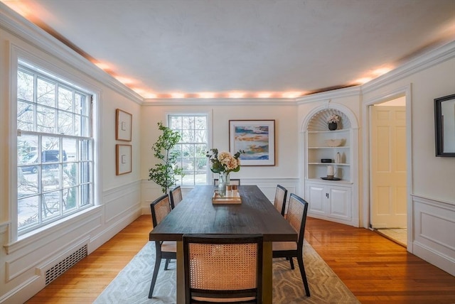 dining area featuring crown molding, light hardwood / wood-style floors, and built in shelves