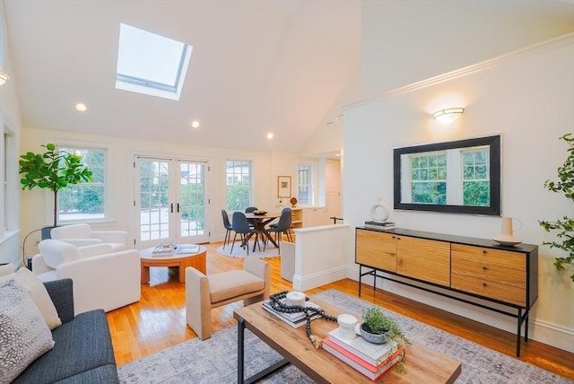 living room featuring a skylight, hardwood / wood-style floors, high vaulted ceiling, and french doors