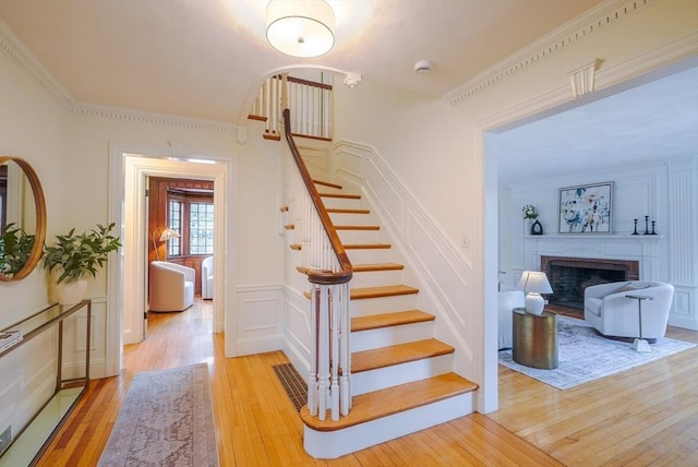 stairway with hardwood / wood-style flooring and crown molding