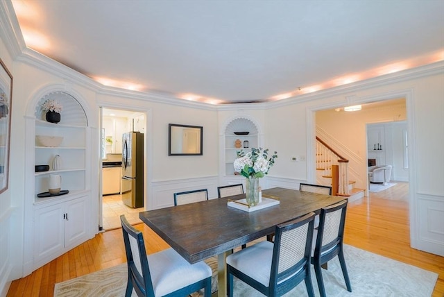 dining space featuring crown molding, built in features, and light hardwood / wood-style flooring