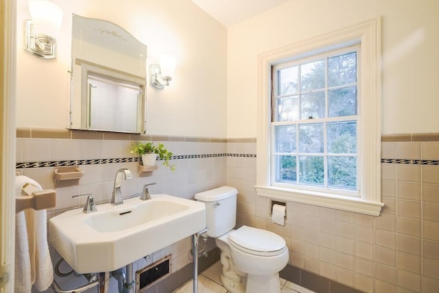 bathroom featuring tile walls, sink, and toilet