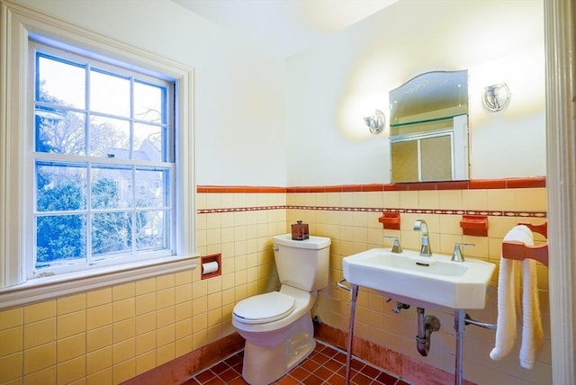 bathroom featuring tile patterned floors, toilet, sink, and tile walls