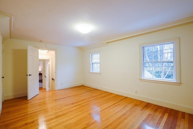 spare room with ornamental molding and light wood-type flooring