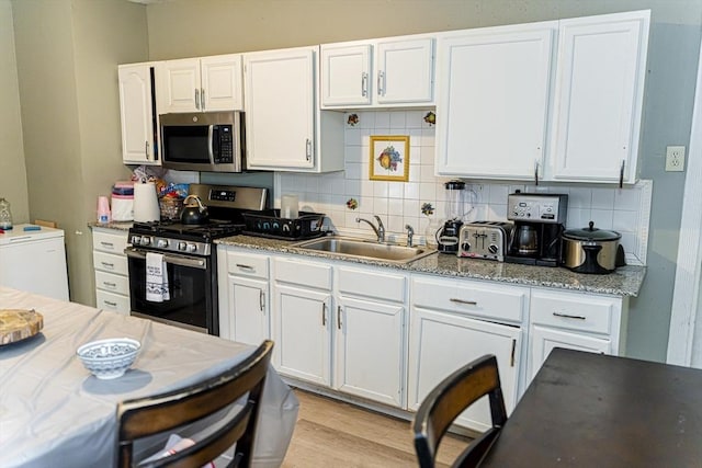 58-60 Virginia St, Springfield, MA 01108 - kitchen with stainless steel appliances, a sink, backsplash, white cabinetry, and light wood finished floors
