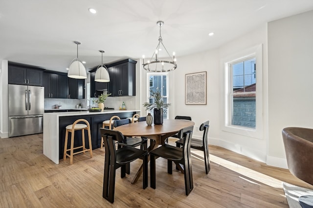 dining area with light wood-type flooring and a chandelier