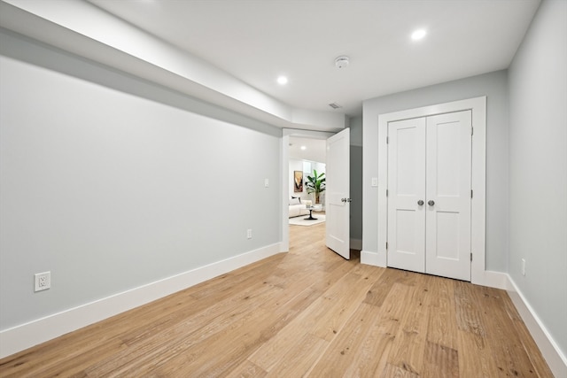 unfurnished bedroom with a closet and light wood-type flooring