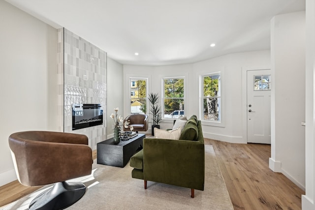 living room featuring light hardwood / wood-style floors and a tiled fireplace