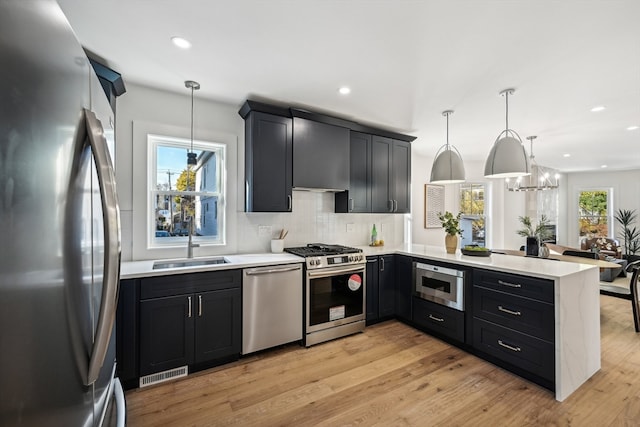 kitchen with kitchen peninsula, a healthy amount of sunlight, decorative light fixtures, and appliances with stainless steel finishes