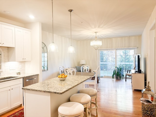 kitchen featuring a kitchen island, white cabinetry, pendant lighting, decorative backsplash, and light hardwood / wood-style floors