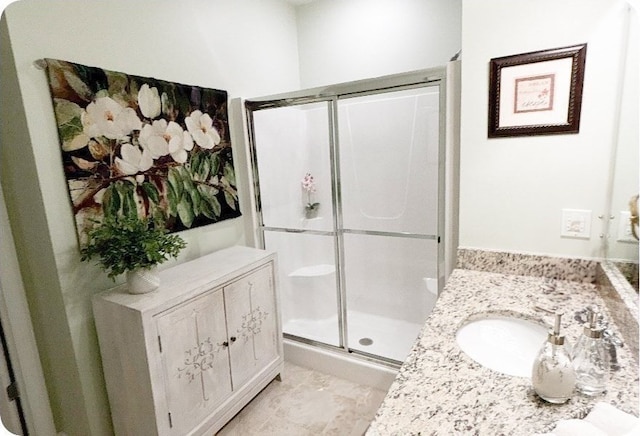 bathroom with a shower with shower door and vanity